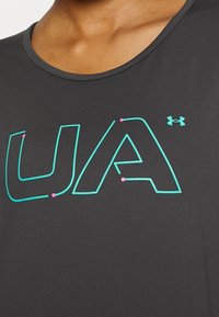 Svart atletisk linne med en stor "UA"-logotyp i turkos med rosa accenter. Slät textur och rund halsringning.