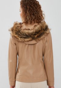 Tan leather jacket with a fur-lined hood, fitted design, smooth texture, and detailed stitching on the back.