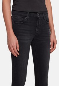Black denim jeans with a slim fit, featuring a classic five-pocket design, subtle stitching, and a button closure at the waist.