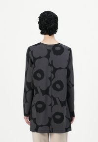 Long-sleeve top in dark gray featuring large black floral patterns. Casual fit with a rounded neckline and side seams. Soft, textured fabric.