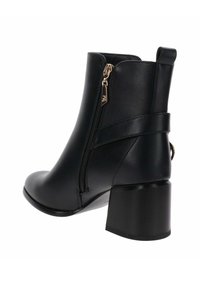 Stivaletto nero realizzato in materiale liscio con chiusura a zip e una fascia curva. Presenta un tacco quadrato e punta rotonda.
