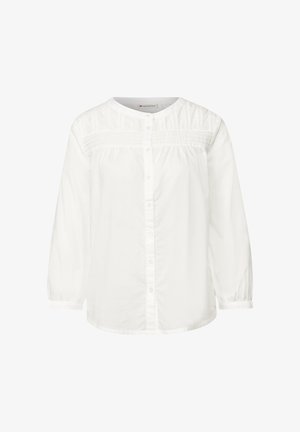 Blusa de algodón blanca con mangas largas, escote redondo, cierre de botones, detalle de yugo texturizado y acentos fruncidos en los hombros.