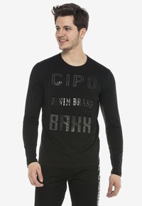 Schwarzes Langarm-T-Shirt mit strukturiertem, reflektierendem Schriftzug: "CIPO", "DENIM BRAND" und "BAKK" in verschiedenen Stilen. Baumwollstoff.