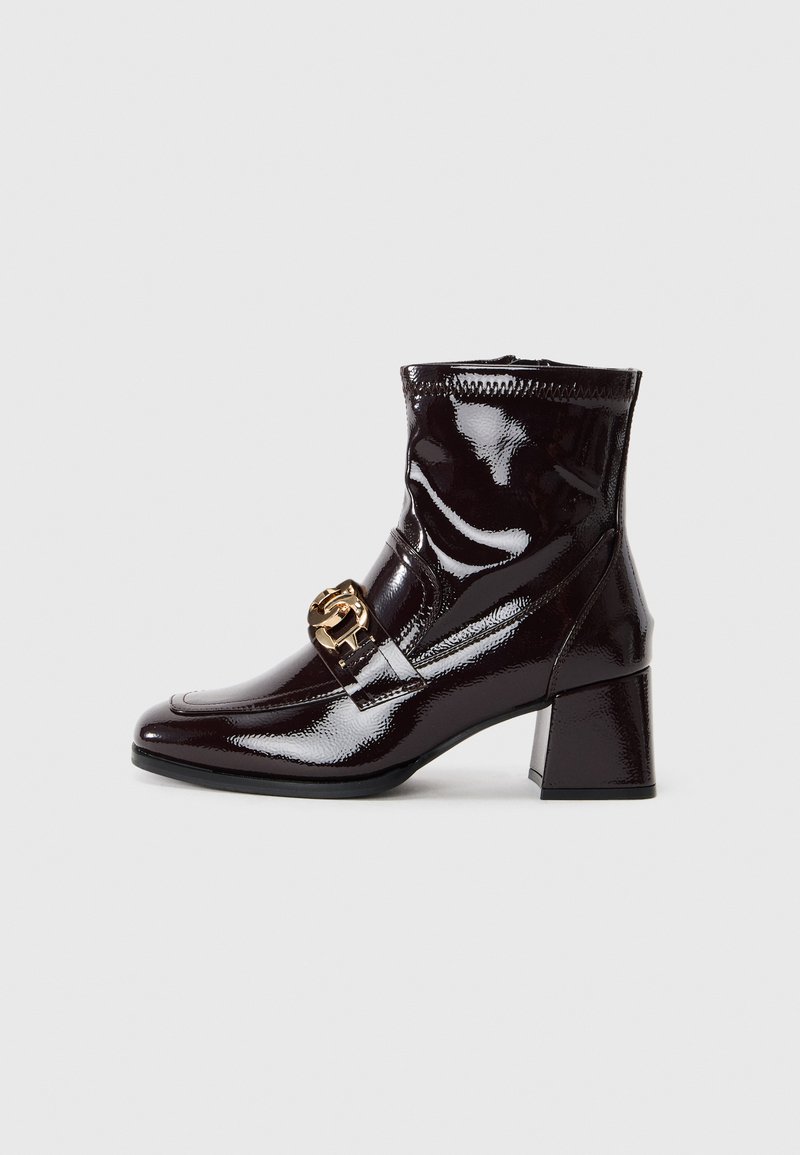 Bottines bordeaux brillantes avec un bout carré, un talon bloc moyen et un détail de boucle en ton doré sur le devant. Texture lisse dans l'ensemble.