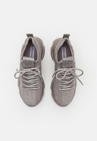 Graue Sneakers mit einem atmungsaktiven Obermaterial, das glitzernde Verzierungen aufweist. Entworfen mit Schnürsenkeln, einem gepolsterten Schaft und einer dicken Gummisohle.