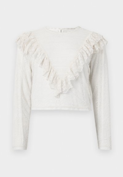 Blouse blanche en dentelle à manches longues avec un bord volanté en forme de V sur le devant et des poignets ajustés, dotée d'un col montant et d'une fermeture à boutons au dos.