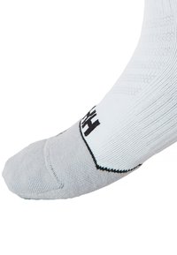 Calcetín deportivo blanco con puntera gris y logo negro, con textura acanalada y talón reforzado para una mayor durabilidad.