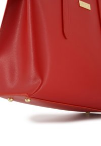 Rote Lederhandtasche mit strukturiertem Oberflächen, ausgestattet mit goldenen Hardware-Akzenten und flachen Bodennägeln für Stabilität. Elegantes, strukturiertes Design.