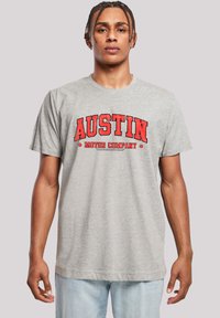 Gray cotton t-shirt featuring bold red text reading "AUSTIN MOTOR COMPANY" in an arch design. Short sleeves and a crewneck style.