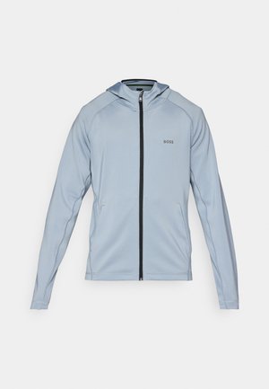 Light blue zip-up hoodie made from a soft fabric. Features a front zipper, side pockets, and a black zipper accent. Logo on the chest.