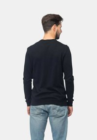 Maglione nero a maniche lunghe con design aderente, realizzato in morbido tessuto lavorato a maglia. Presenta un collo rotondo e polsini e orlo a coste.