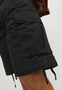 Zwarte cargoshorts van duurzaam materiaal, met zijzakken, een trekkoord bovenkant en een gestructureerd oppervlak. Minimalistische ontwerpelementen.