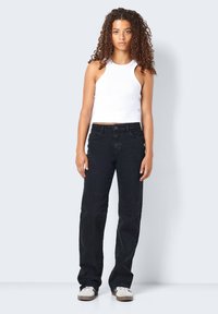 Sorte denimbukser med rett benskjæring, med frontlommer og knappelukking, kombinert med en hvit ribbestrikket tanktop.