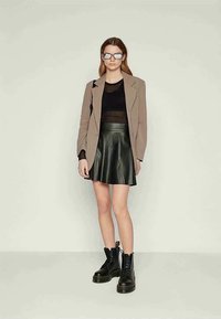 Brun rutete blazer, svart ribbet topp, svart skinnspraykjole og svarte militære støvler. Square solbriller fullfører looken.