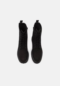Černé kožené kotníkové boty se hladkým povrchem, šněrováním vpředu a bočními zipy. Silné podešve a prošívání kolem okrajů.
