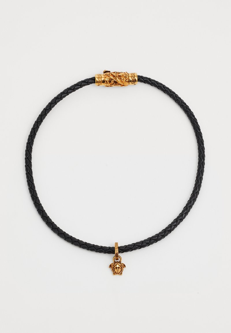 Collana in pelle intrecciata nera con chiusura decorativa in tono oro, dotata di un ciondolo a forma di testa di leone e dettagli intricati.