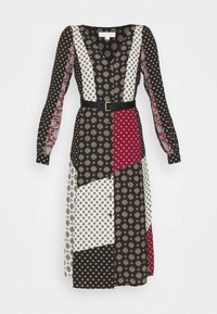 Dlouhý midi šaty s patchworkovými vzory v černé, bílé a červené barvě, s výstřihem do V a černým opaskem v pase.