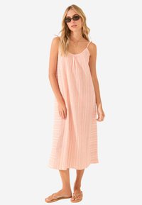 Abito maxi a righe rosa e bianche con spalline sottili e scollo arricciato, abbinato a flip-flop e occhiali da sole. Texture del tessuto morbida.