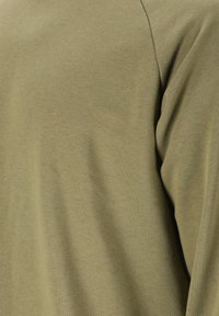 Olivgrön, långärmad bomullsskjorta med en mjuk textur och enkelt design. Synliga sömdetaljer längs axeln.