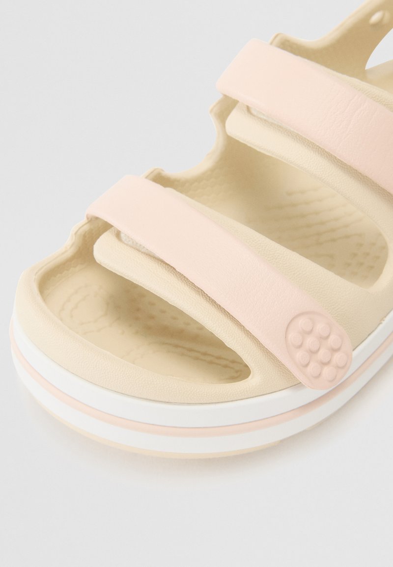 Sandal leggera con soletta in gomma beige, cinturini sintetici rosa, plantare testurizzato e dettaglio circolare sul lato.