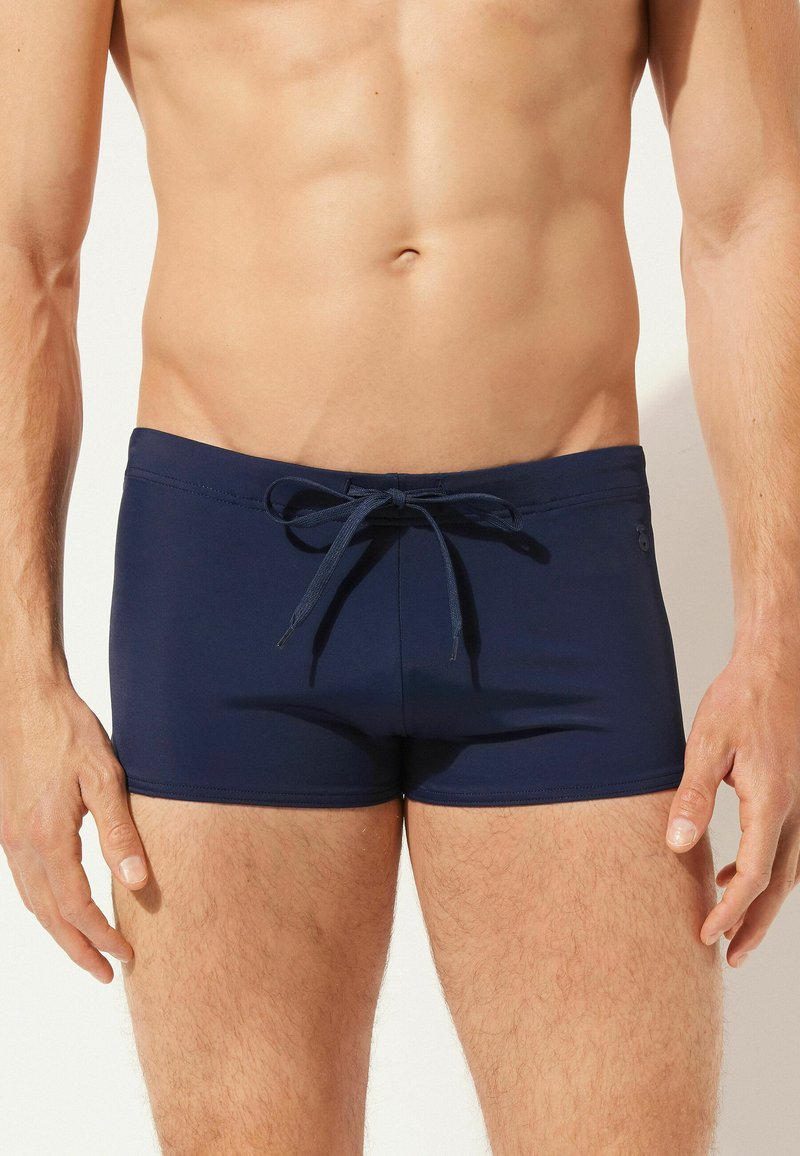 Navyblaue Badehose mit einem elastischen Bund und Kordelzug. Glatter, dehnbarer Stoff mit minimalen Nähten und ohne zusätzliche Muster.