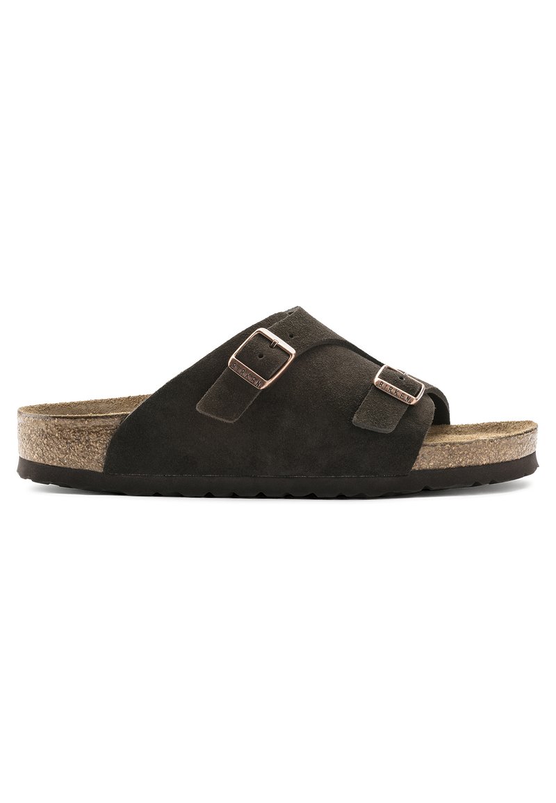 Sandale à glisser en suede marron avec deux boucles en métal ajustables, une semelle en liège et une semelle en caoutchouc texturée, conçue pour un confort et une facilité de port.