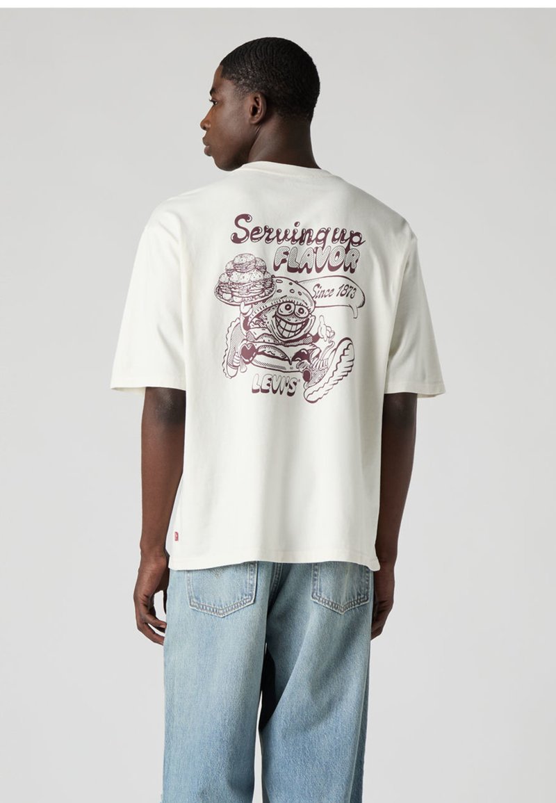 Λευκό βαμβακερό t-shirt με κοντά μανίκια, που διαθέτει πολύχρωμο γραφικό σχέδιο στην πλάτη με κείμενο και χαρακτήρα φαγητού.