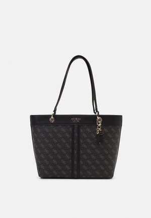 Sort tote-taske med gentaget monogrammønster, to skulderstropper, gyldent logo "GUESS EST 1981" og dekorativt gyldent vedhæng på siden.