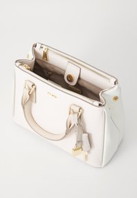 Sac fourre-tout beige et blanc avec quincaillerie dorée, doubles poignées, fermeture éclair et surface texturée. L'intérieur comporte des poches et un bouton-pression.