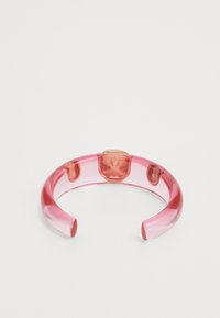 Transparent pink acrylic cuff bracelet with a solid gold-tone accent in the center, featuring a smooth texture and open ends.