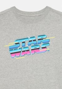 Siva majica z barvnim logotipom "STAR WARS" v modri, roza in črni barvi z grafičnimi poudarki; bombažni material, krojen vrat.