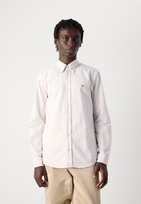 Camicia a righe chiare in morbido cotone, con chiusura a bottoni sul davanti, un piccolo logo sul petto e maniche lunghe. Toni neutri.
