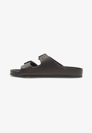 Sort slidesandal i glat syntetisk materiale, med to justerbare stropper, en flad sål og en struktureret ydersål for godt greb.