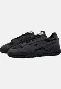 Scarpe da ginnastica nere con una combinazione di materiale scamosciato e mesh, dotate di una suola testurizzata e di un design aerodinamico.