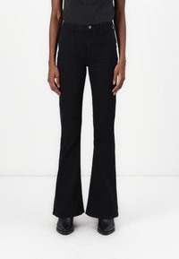 Black flared pants made of denim, featuring a high waist, front pockets, and a smooth texture. Paired with black heeled ankle boots.