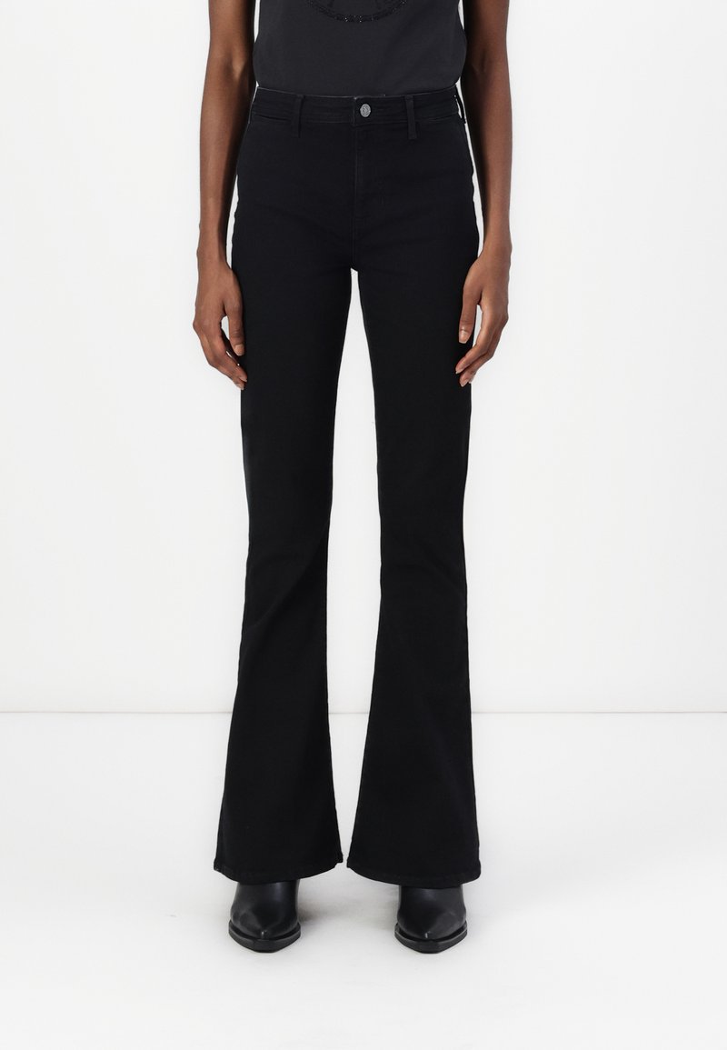 Black flared pants made of denim, featuring a high waist, front pockets, and a smooth texture. Paired with black heeled ankle boots.