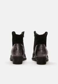 Schwarze Knöchelstiefel aus Wildleder und krokodilgeprägtem Leder. Sie verfügen über einen niedrigen Blockabsatz und seitliche Reißverschlüsse für ein einfaches An- und Ausziehen.