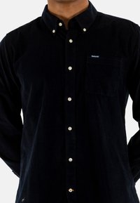 Navyblauwe corduroy overhemd met een button-down kraag, een borstzak en beige knopen. Beschikt over een zachte textuur en een klassiek ontwerp.