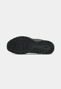 Melnas sporta apavu zole ar faktūru, kas sastāv no taisnstūra un apaļām grabēm, nodrošinot saķeri un izturību. Redzams Nike logotips.