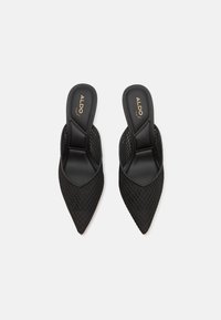 Mule-uri negre din plasă cu un design cu vârf ascuțit, având un superior texturat și o talpă interioară netedă. Logo embosat pe talpa interioară.