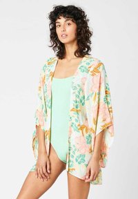 Kimono floral en una tela ligera con tonos durazno, verde y amarillo, que presenta mangas abiertas y un corte relajado sobre un traje de baño menta.