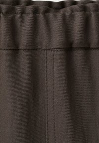 Tissu côtelé brun foncé avec coutures verticales visibles et une taille élastique en haut.