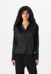 Black satin long-sleeve shirt with a button-up front, notch collar, and single chest pocket, featuring a smooth, glossy texture.