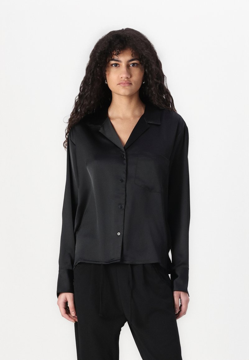 Black satin long-sleeve shirt with a button-up front, notch collar, and single chest pocket, featuring a smooth, glossy texture.