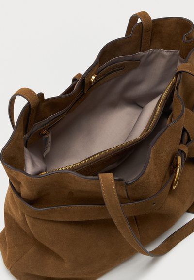 Καφέ σουέντ τσάντα ώμου με μπεζ υφασμάτινη επένδυση στο εσωτερικό, κεντρικό φερμουάρ στη μεσαία θήκη και διπλές λαβές.