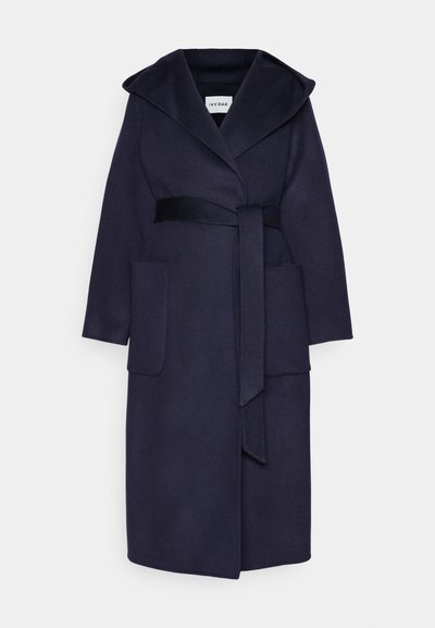 Navy wool blend coat with a large hood, front pockets, and a tie belt. The fabric has a smooth texture and a straight cut silhouette.