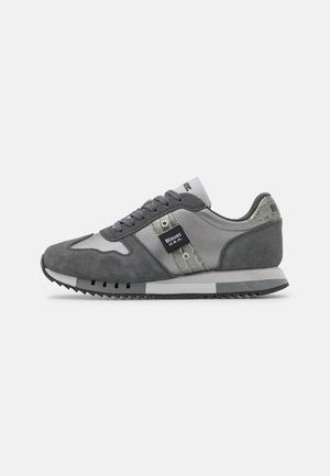 Szare i ciemnoszare zamszowe i materiałowe sneakersy z teksturowanymi akcentami, sznurowane z przodu, z etykietą "Blauer U.S.A." na bocznym panelu.
