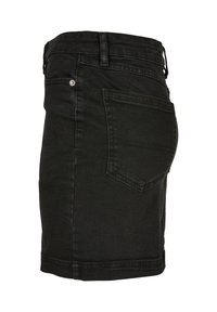 Zwarte denim rok met achterzak, ceintuurlussen en metalen klinknagel op de zijnaad, van de zijkant getoond op een witte achtergrond.