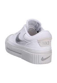 Witte Nike sneakers met een gestructureerde zilveren swoosh, voorzien van een gestructureerde witte rubberen zool en een klein Nike-logo op de hieltab.