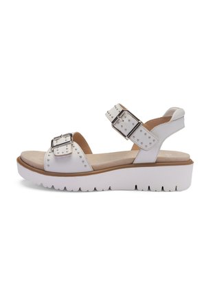 Weiße Sandale mit zwei verstellbaren Riemen mit silbernen Schnallen, Nietenakzenten und einer dicken, strukturierten weißen Sohle.